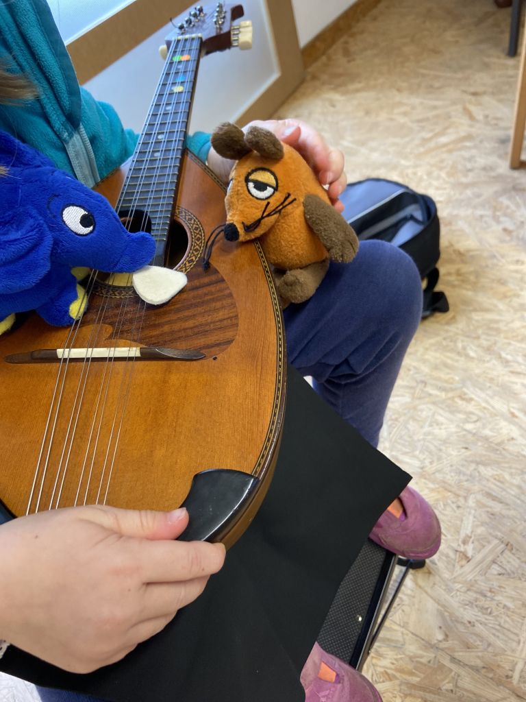 Die Maus und der kleine blaue Elefant helfen dem Kind das Instrument Mandoline zu erklären.